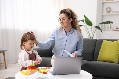 Photo of Work-family balance. Single mother with document and her daughter indoors