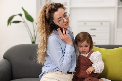 Photo of Work-family balance. Single mother talking on smartphone and her daughter indoors