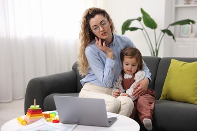 Work-family balance. Single mother talking on smartphone and her daughter indoors