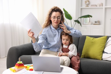 Photo of Work-family balance. Single mother with document talking on smartphone and her daughter indoors