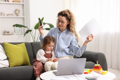 Photo of Work-family balance. Single mother with smartphone and her daughter indoors