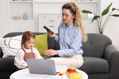 Photo of Work-family balance. Single mother with smartphone and her daughter indoors