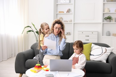 Photo of Work-family balance. Single mother with document and her daughters indoors