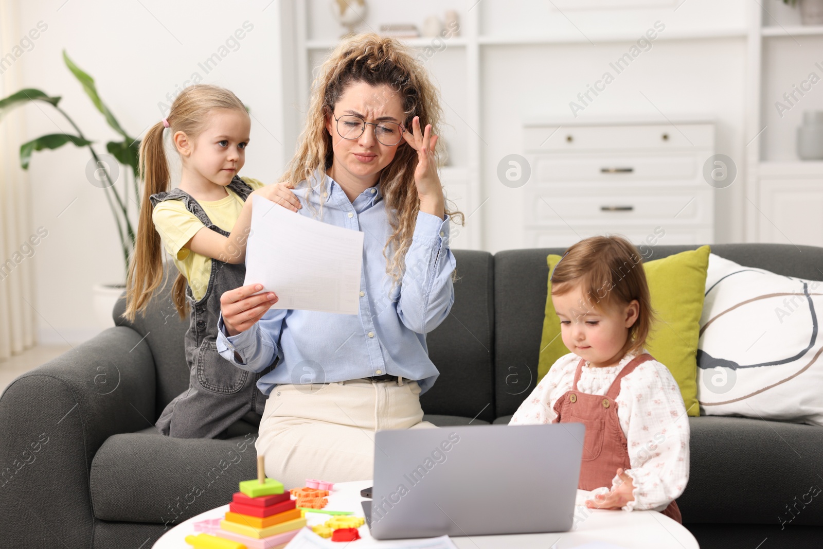 Photo of Work-family balance. Single mother with document and her daughters indoors