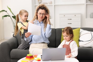 Photo of Work-family balance. Single mother with document and her daughters indoors