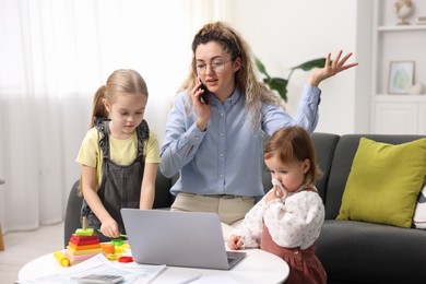 Work-family balance. Single mother talking on smartphone and her daughters at home