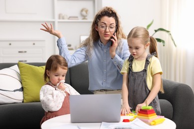 Work-family balance. Single mother talking on smartphone and her daughters at home