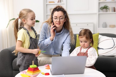 Work-family balance. Single mother talking on smartphone and her daughters at home