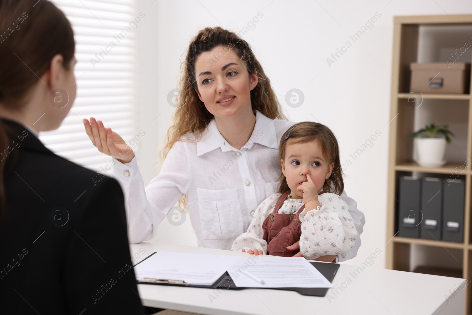 Photo of Single mother with her daughter during job interview at table indoors