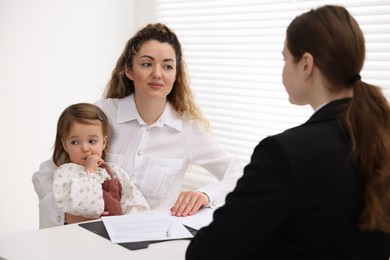 Photo of Single mother with her daughter during job interview at table indoors