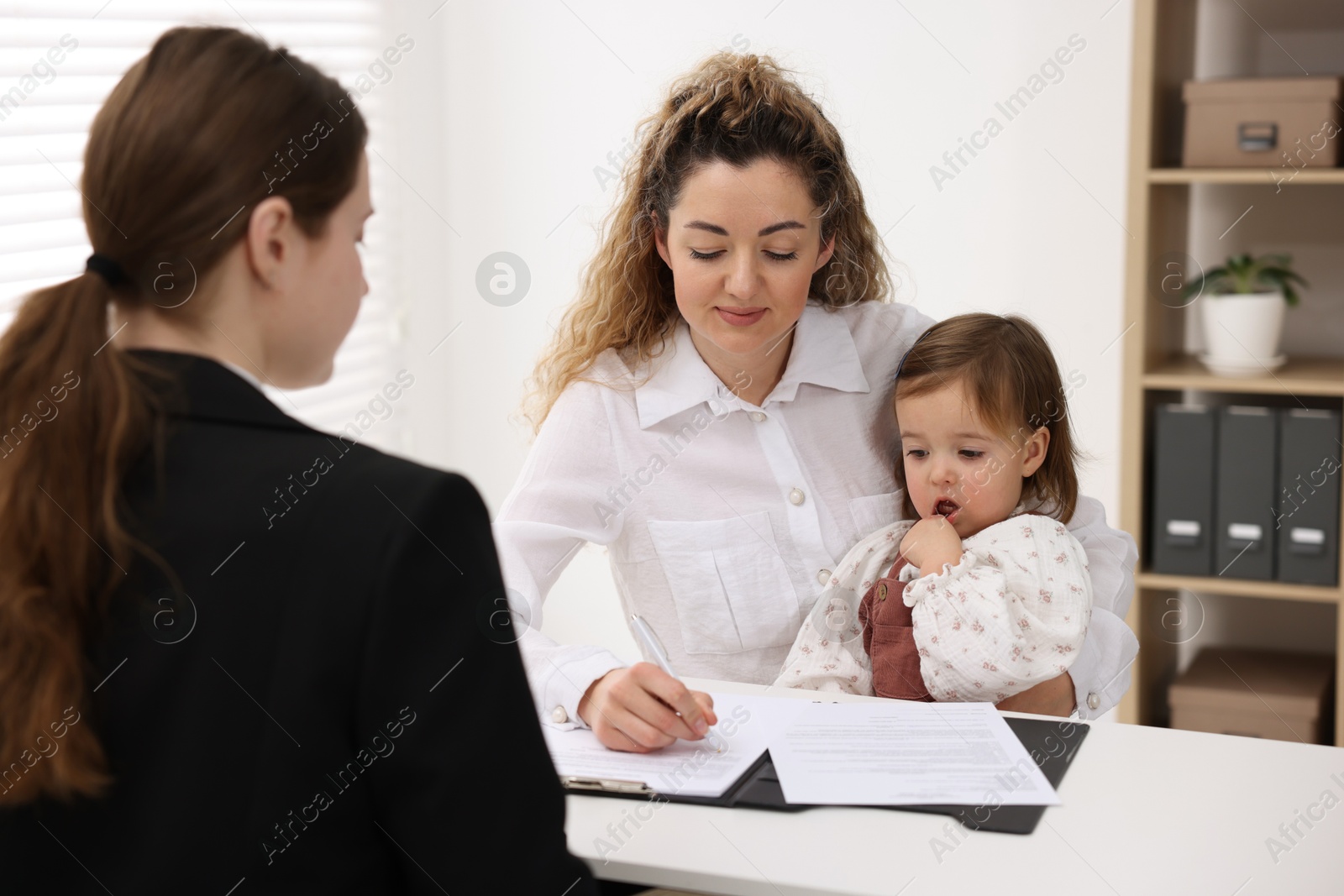 Photo of Single mother with her daughter during job interview at table indoors