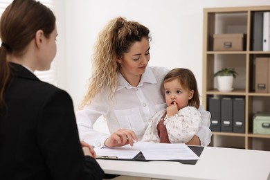 Photo of Single mother with her daughter during job interview at table indoors