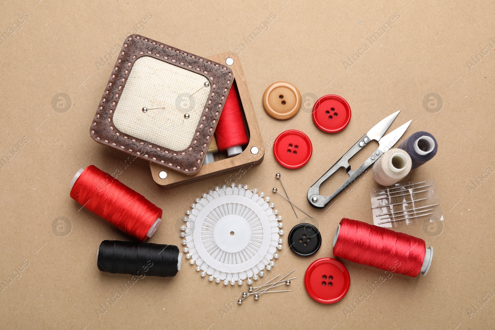 Photo of Different sewing supplies on beige background, flat lay