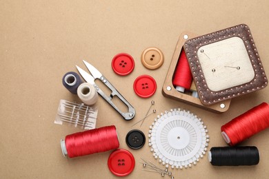 Photo of Different sewing supplies on beige background, flat lay