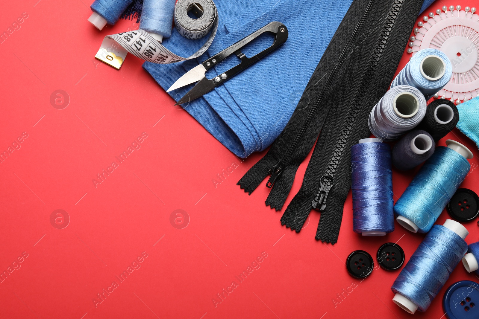 Photo of Different sewing supplies on red background, flat lay. Space for text