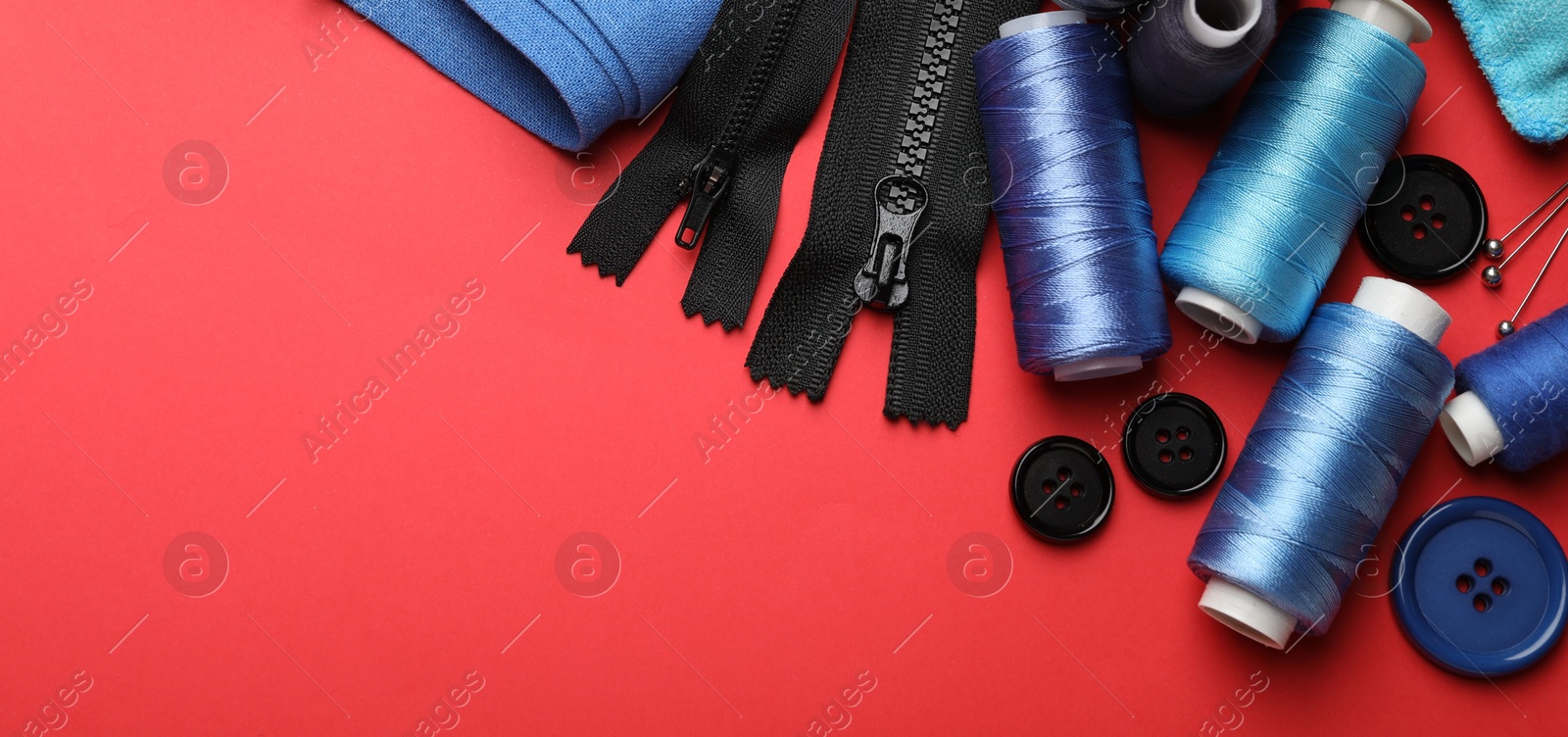 Photo of Different sewing supplies on red background, flat lay. Space for text