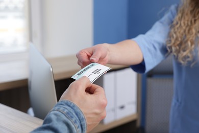 Photo of Patient giving medical insurance card to receptionist in clinic, closeup