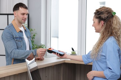 Photo of Receptionist taking payment from patient via terminal in clinic