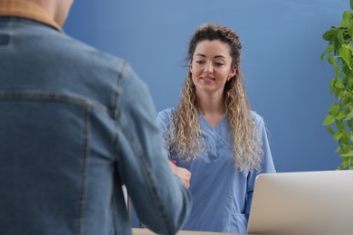 Photo of Smiling receptionist taking payment from patient via terminal in clinic