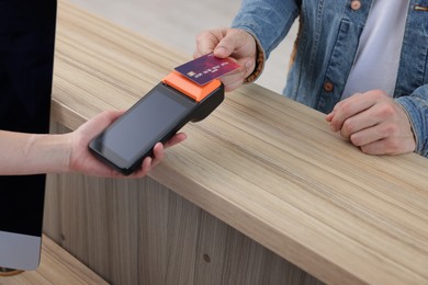 Photo of Receptionist taking payment from patient via terminal at counter in clinic, closeup