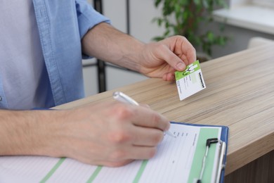 Photo of Patient with medical insurance card filling document at counter in clinic, closeup