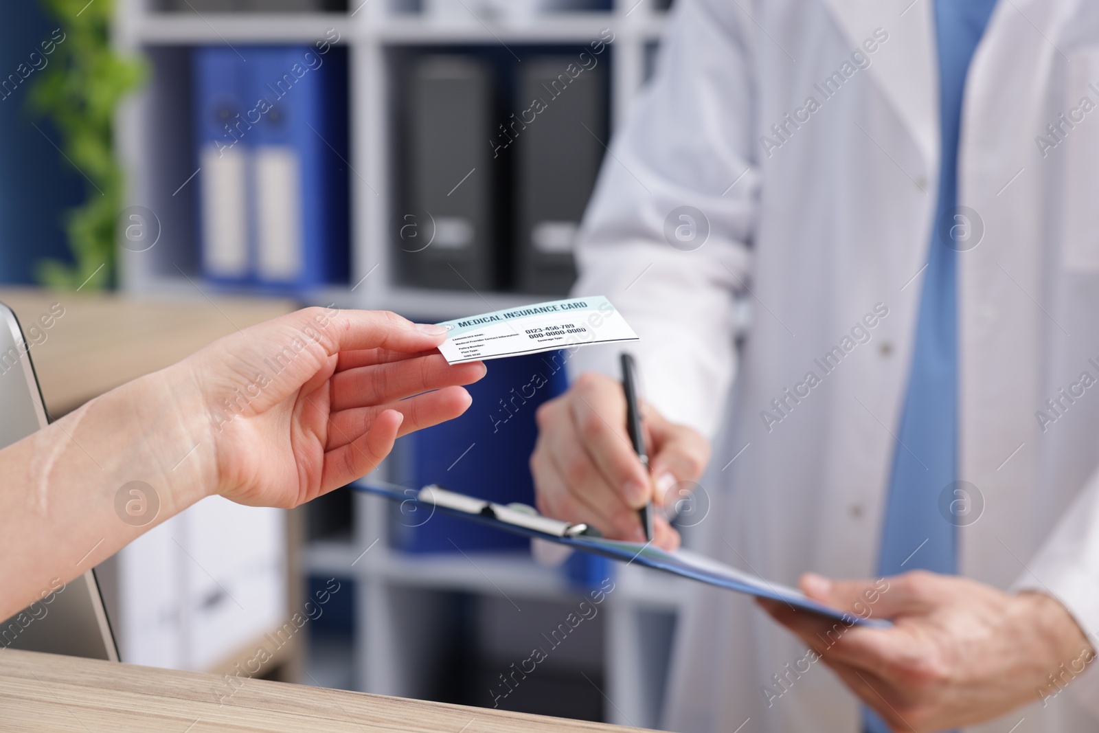 Photo of Patient giving medical insurance card to receptionist in clinic, closeup