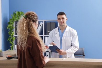 Patient giving medical insurance card to smiling receptionist in clinic