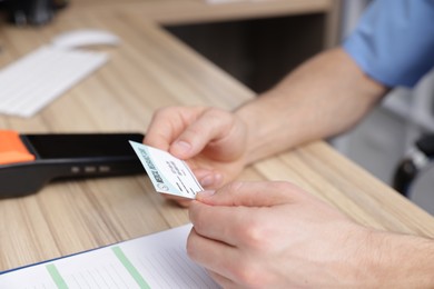 Photo of Receptionist with medical insurance card at wooden table, closeup