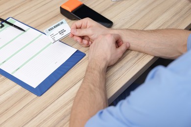 Receptionist with medical insurance card at wooden table, closeup