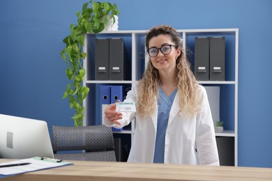 Smiling receptionist giving medical insurance card at counter in clinic