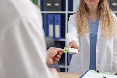 Patient giving medical insurance card to receptionist in clinic, closeup