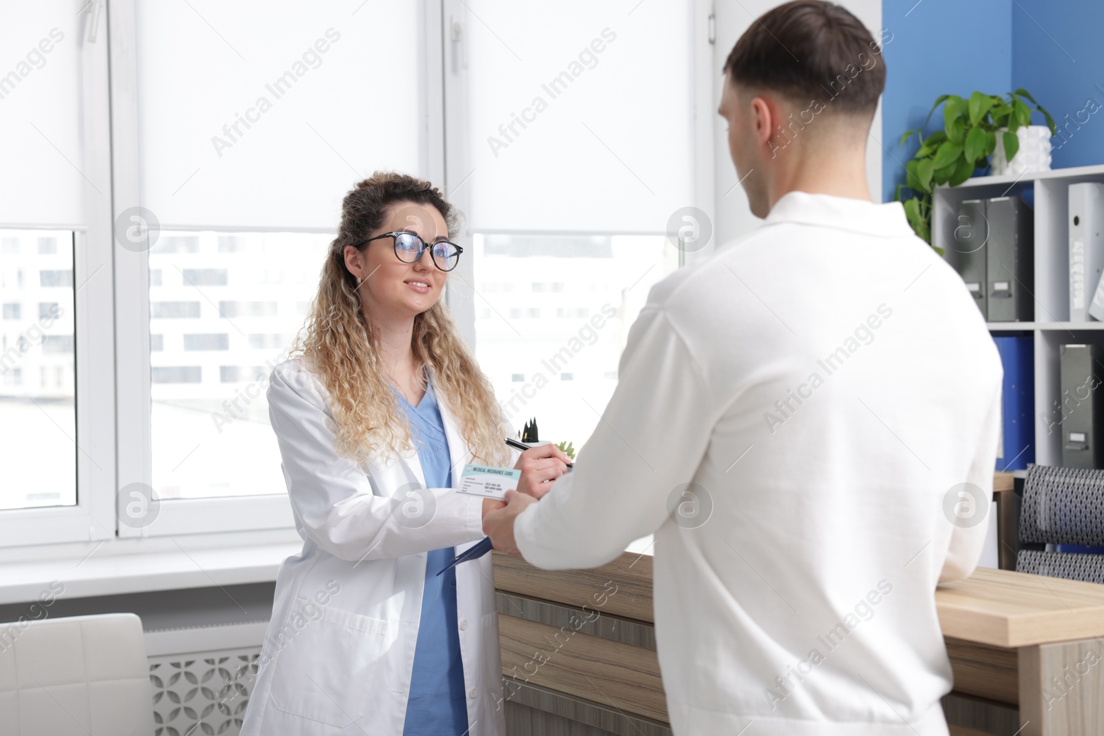 Photo of Patient giving medical insurance card to receptionist in clinic