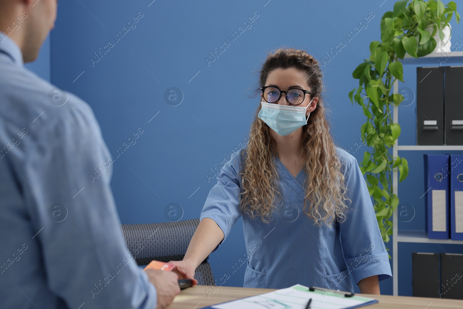 Photo of Receptionist taking payment from patient via terminal in clinic