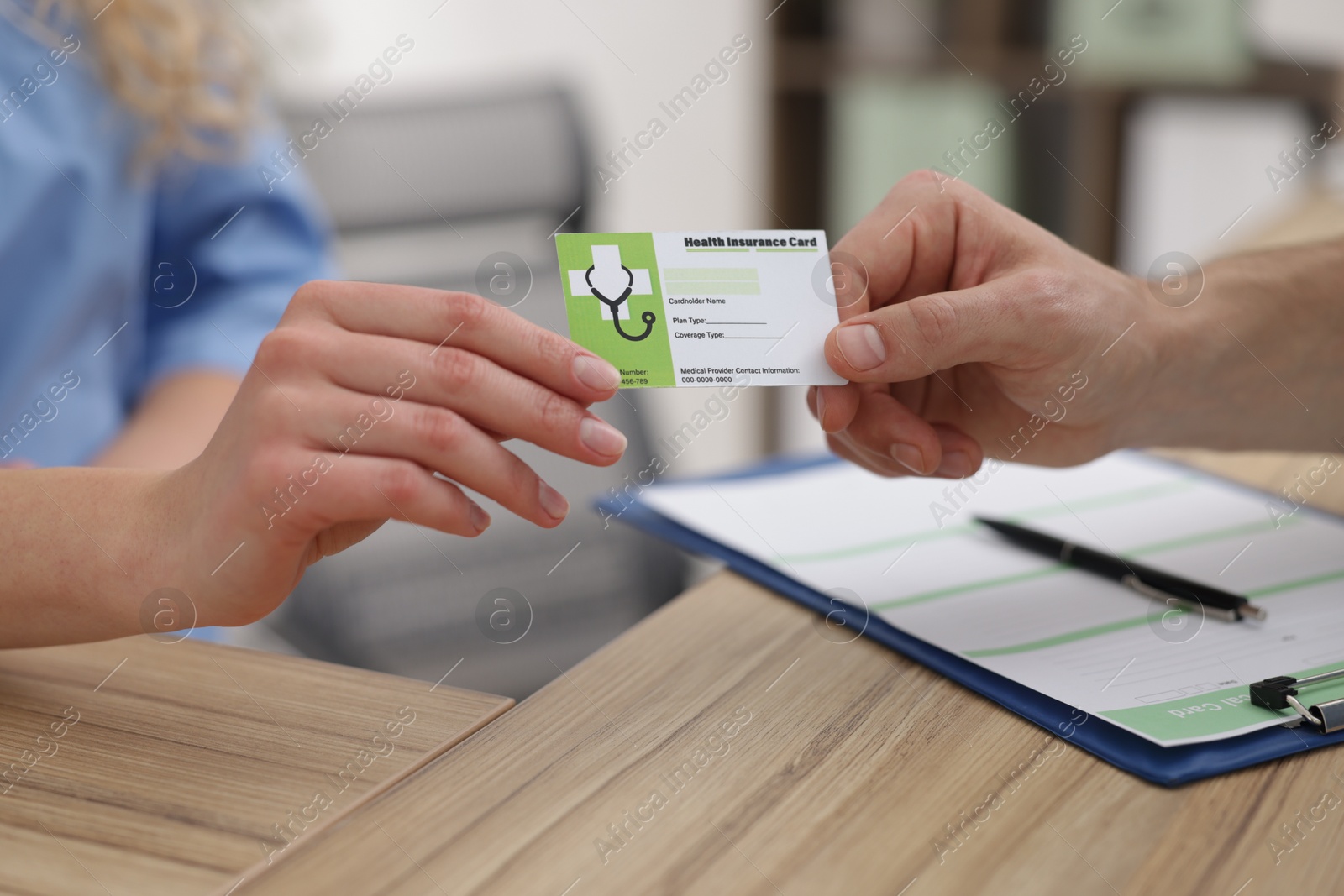 Photo of Patient giving medical insurance card to receptionist at wooden counter in clinic, closeup