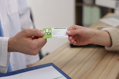 Photo of Patient giving medical insurance card to receptionist at wooden counter in clinic, closeup