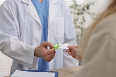 Photo of Patient giving medical insurance card to receptionist in clinic, closeup