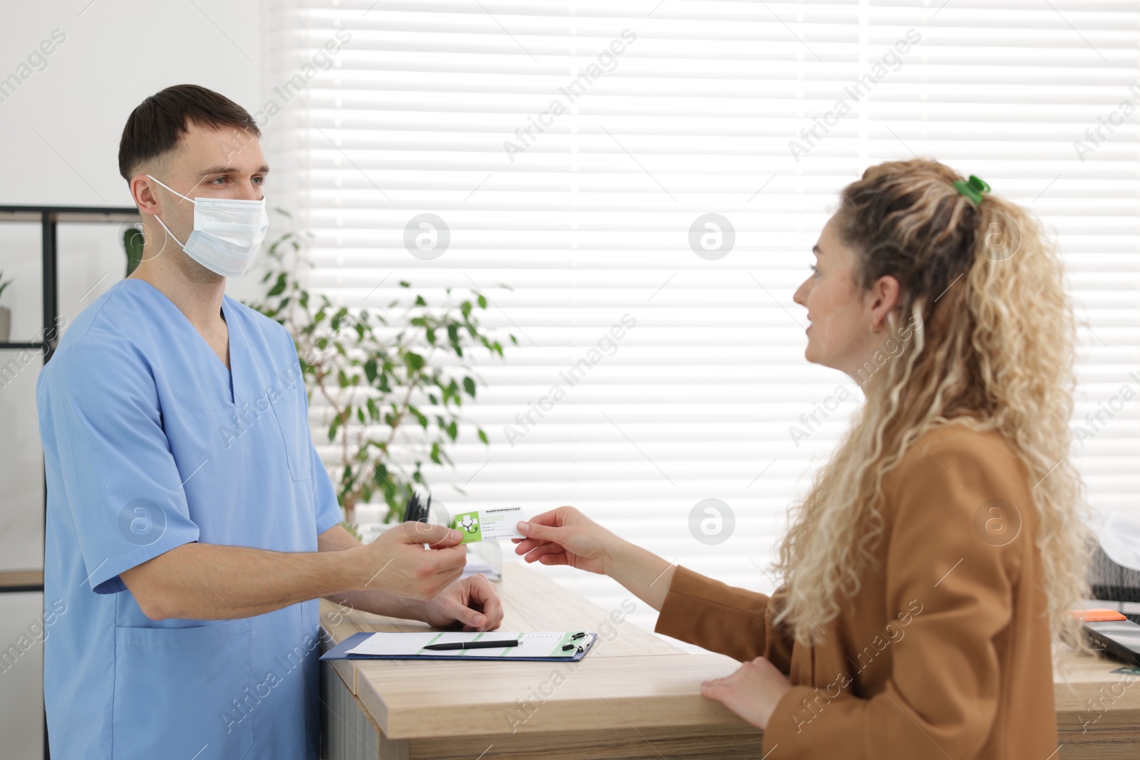 Photo of Patient giving medical insurance card to receptionist in clinic