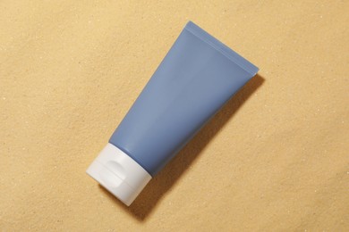 Tube of sun protection product on sand, top view