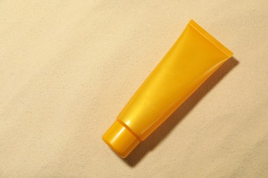 Photo of Tube of sun protection product on sand, top view. Space for text