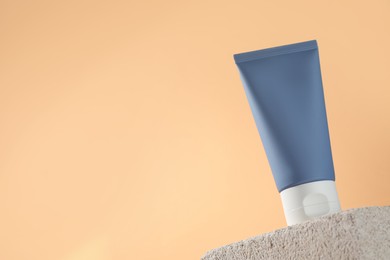 Photo of Tube of sun protection product on stone against beige background, low angle view