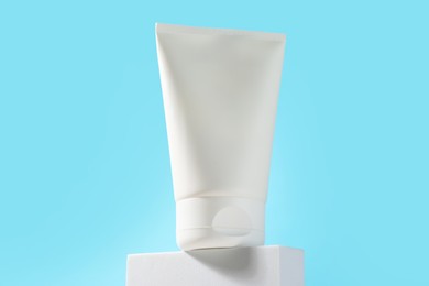 Bottle of sun protection product on podium against light blue background