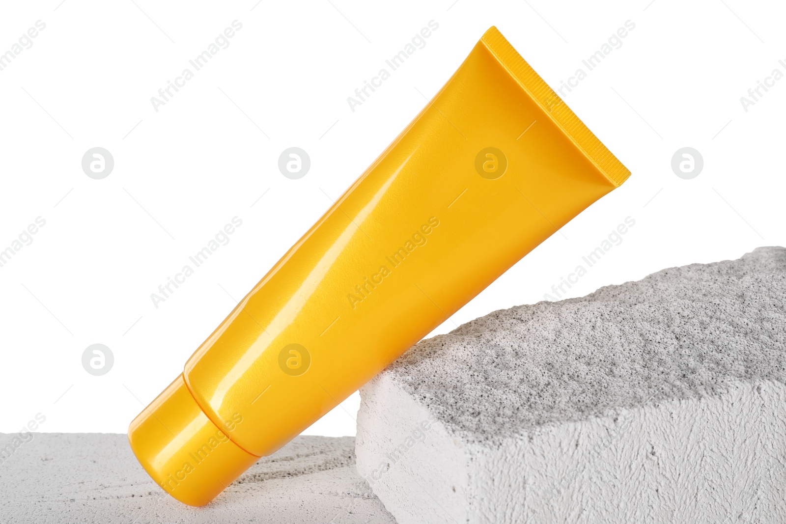 Photo of Tube of sun protection product on concrete block against white background