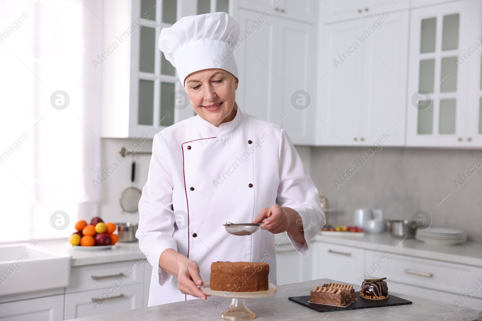 Photo of Professional pastry chef making cake at table in kitchen