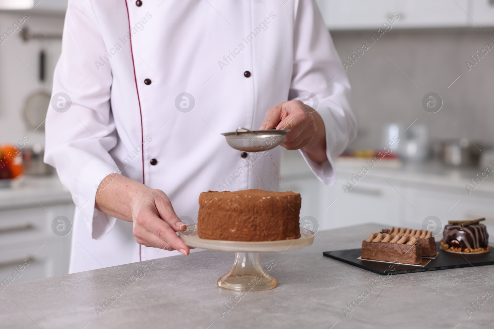 Photo of Professional pastry chef making cake at table in kitchen, closeup