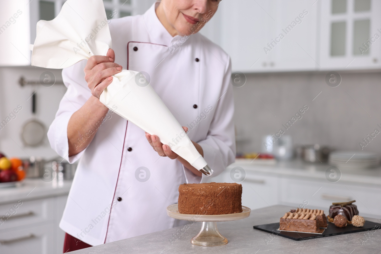 Photo of Professional pastry chef making cake at table in kitchen, closeup