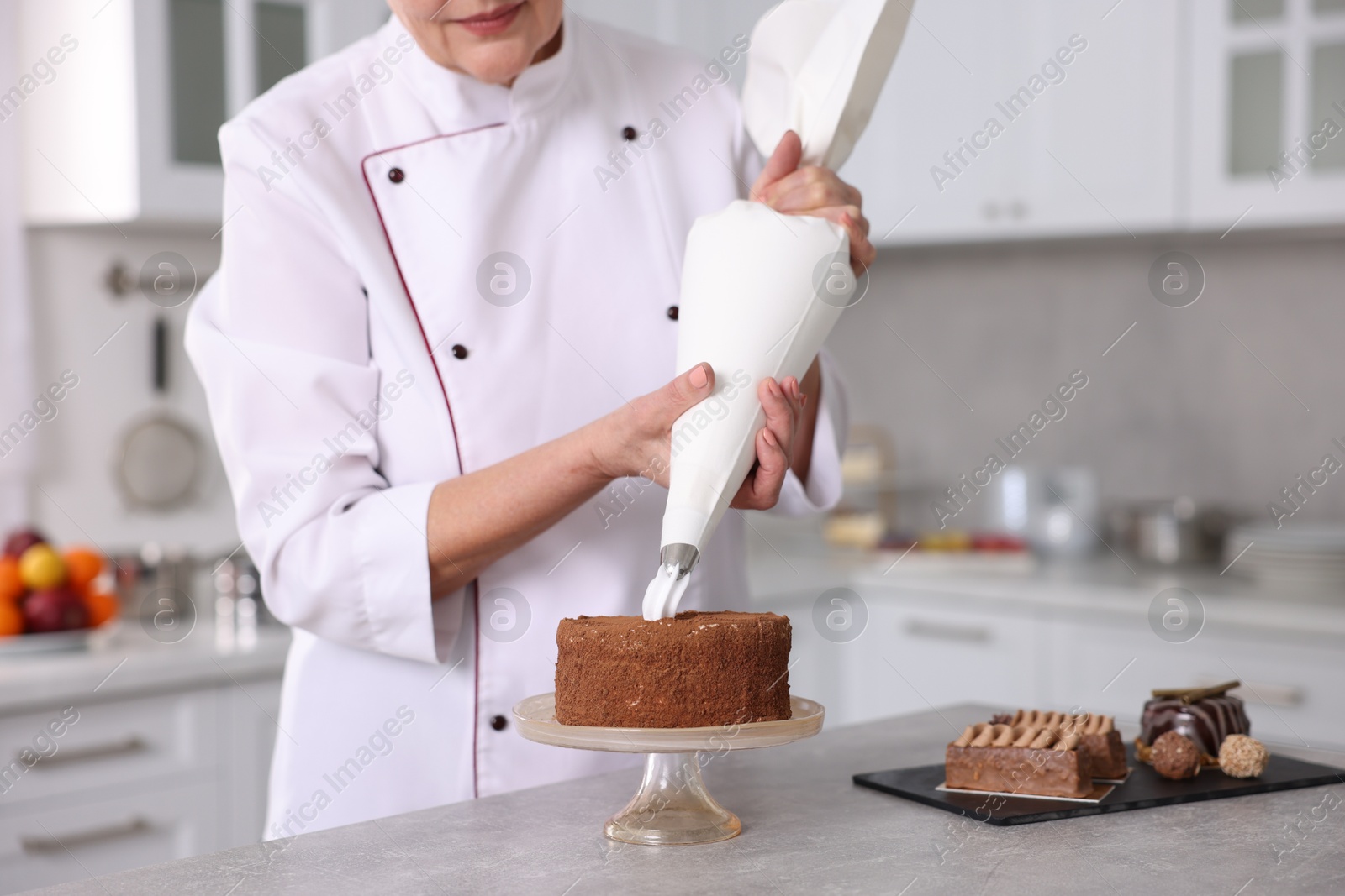 Photo of Professional pastry chef making cake at table in kitchen, closeup