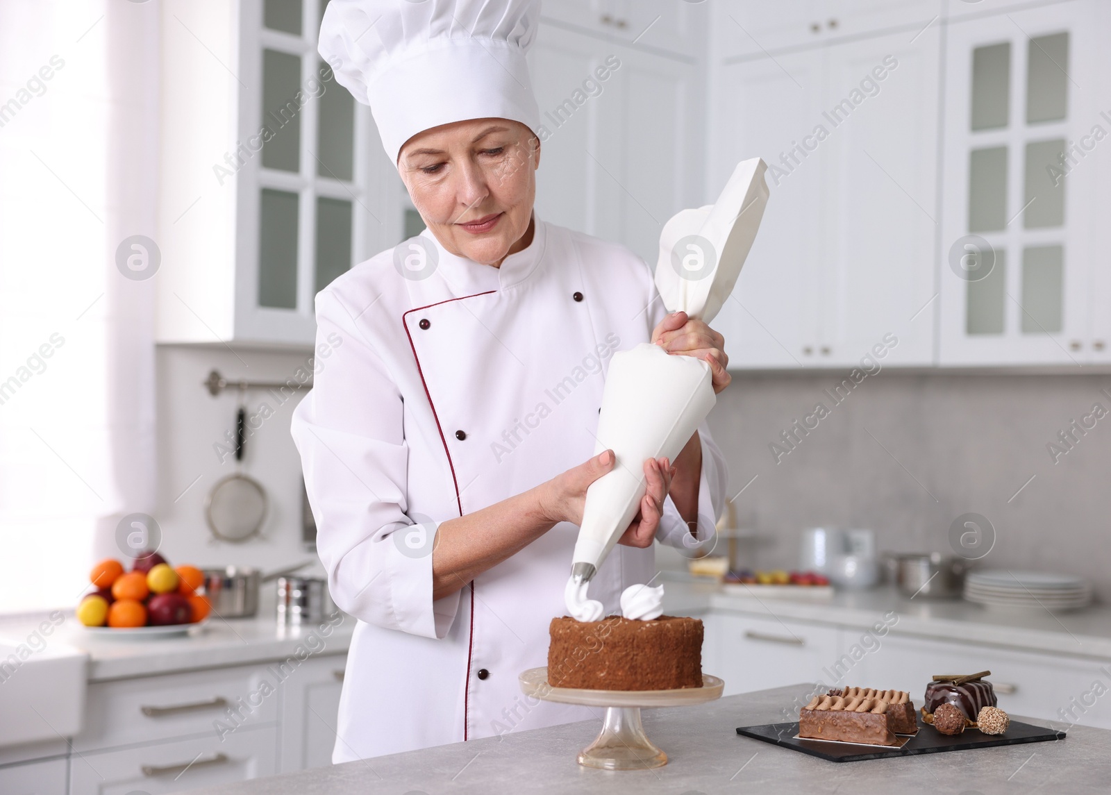 Photo of Professional pastry chef making cake at table in kitchen