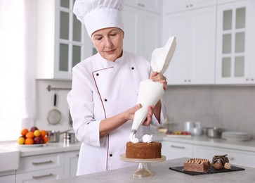 Photo of Professional pastry chef making cake at table in kitchen