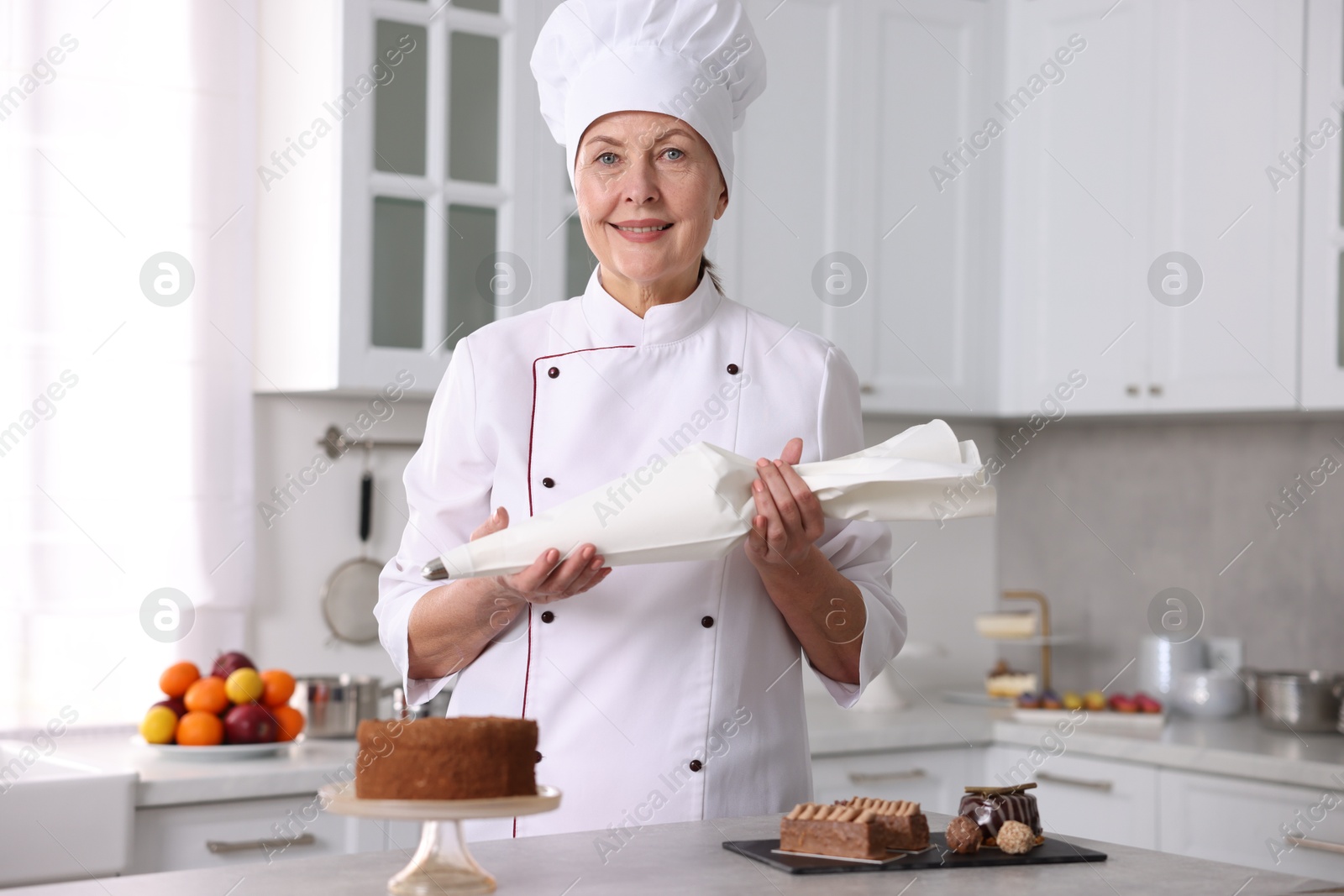 Photo of Professional pastry chef with desserts at table in kitchen