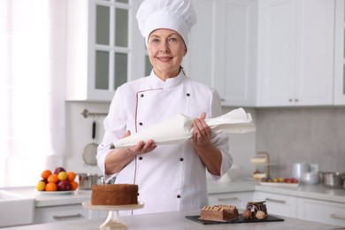 Photo of Professional pastry chef with desserts at table in kitchen